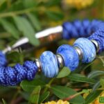 Blauwe Paracord heren gedenkarmband met transparante blauwe crematie-as glasbedel tussen twee gezandstraalde glasbedels.