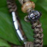 Staande paracord armband met crematie-as glasbedel en rvs Boeddha bedel.