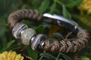 Heren gedenkarmband met bruine Sailrope en bruine crematie-as glasbedel tussen twee gezandstraalde glasbedels van voren gefotografeerd.