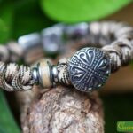 Gemêleerde Sailrope gedenkarmband met licht beige rvs crematie-as bedel naast een rvs hart button bedel.