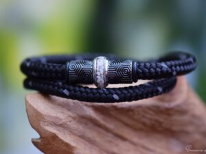 Zwarte herenarmband met crematie-as in middelste rvs bedel tussen designbedels.