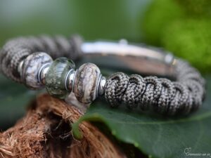 Heren gedenkarmband met grijze geknoopte band en drie glasbedels waarvan de middelste transparant grijs is met crematie-as.